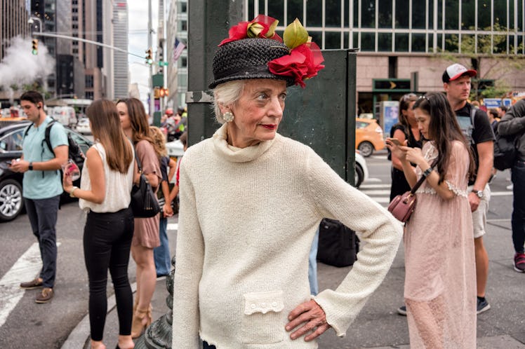 A woman in a beige sweater and a black hat with a crowd behind her by Melissa O’Shaughnessy in New Y...