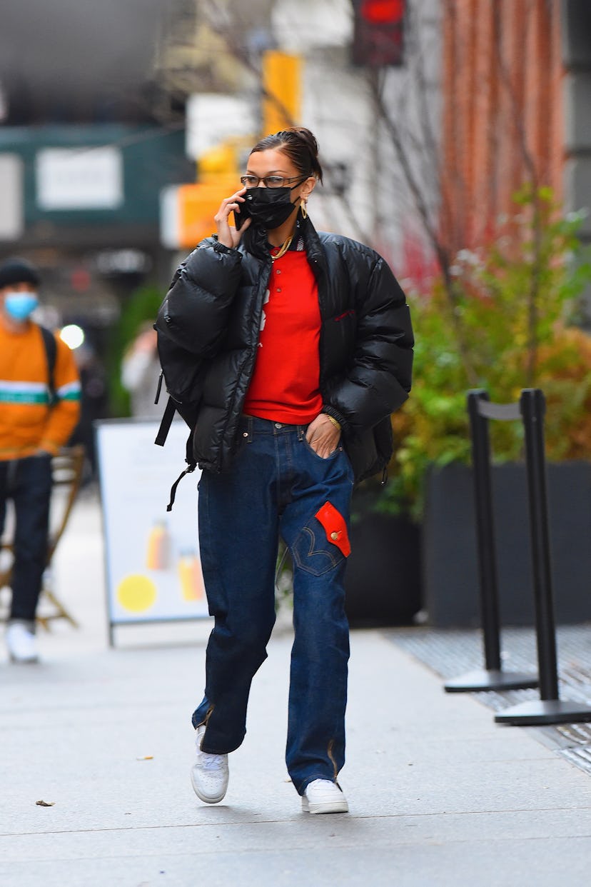 Bella Hadid in black puffer jacket, walking down the street while talking on her phone