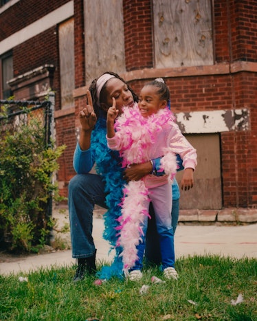 A mom with a blue feather scarf and a girl with a pink feather scarf posing for Matthew So’s series,...