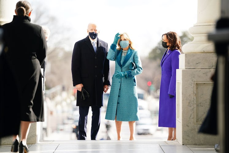 Joe Biden in a black coat and suit and Dr. Jill Biden in a blue dress, coat and gloves standing