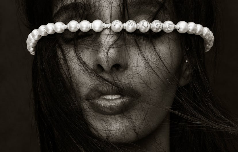 A model with messy dark hair over her hair and a pearl necklace by Wilfredo Rosado on her forehead