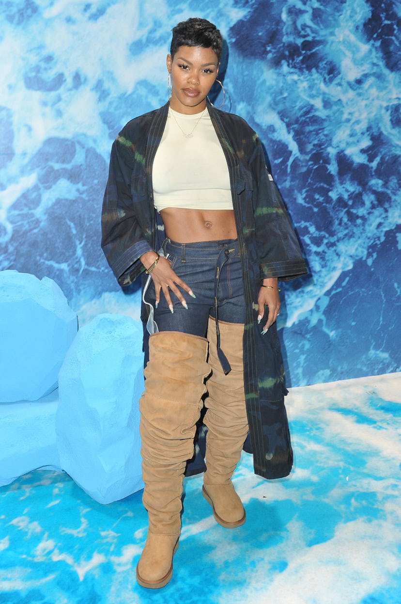 Teyana Taylor wearing a white top, green kimono, denim jeans, and an over-the-knee Beige Ugg boots