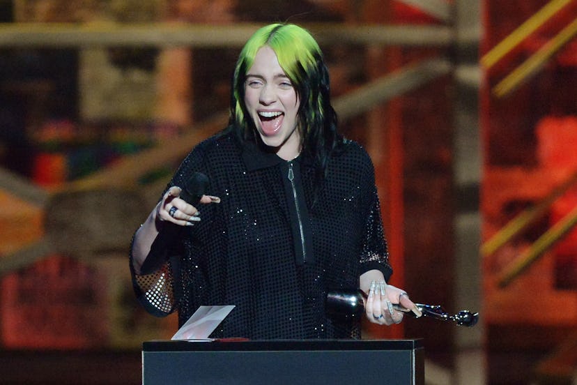 Billie Eilish in a black outfit with black-green hairstyle on stage