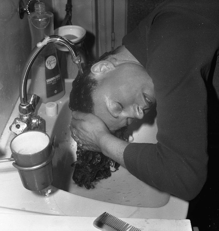 A woman washing her hair above a sink