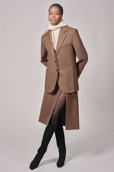 A model in a brown blazer, matching skirt with a slit and a hooded sweater underneath by Phillip Lim