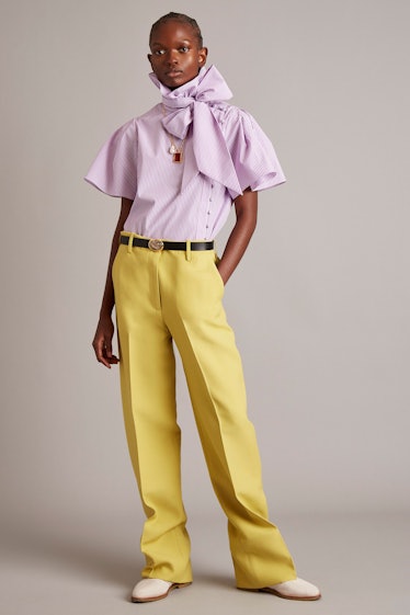 A model in a purple shirt with a bow and yellow pants by Adam Lippes