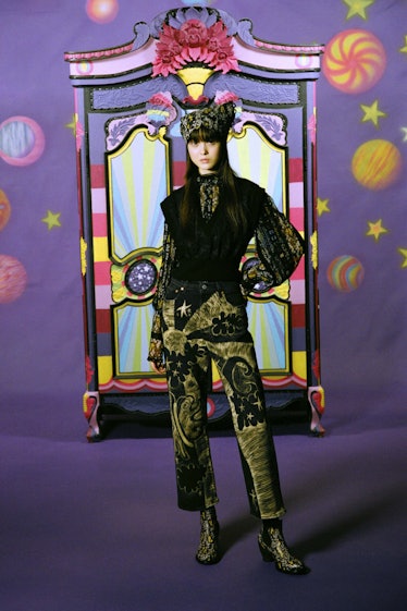 A model in a dark green jumpsuit with illustrations on it by Anna Sui