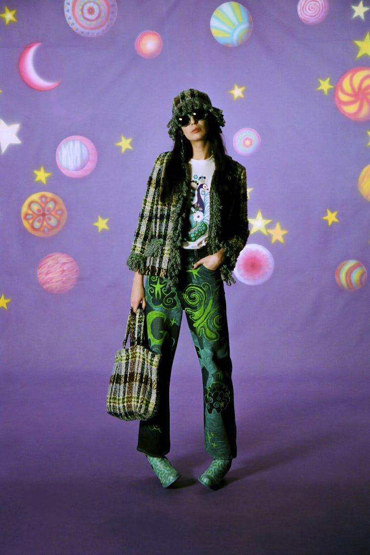 A model in green pants along with a green blazer, hat and bag all in plaid by Anna Sui