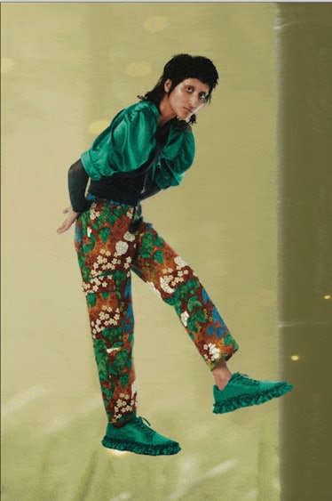A model in a green silk top and floral pants with green sneakers by Collina Strada