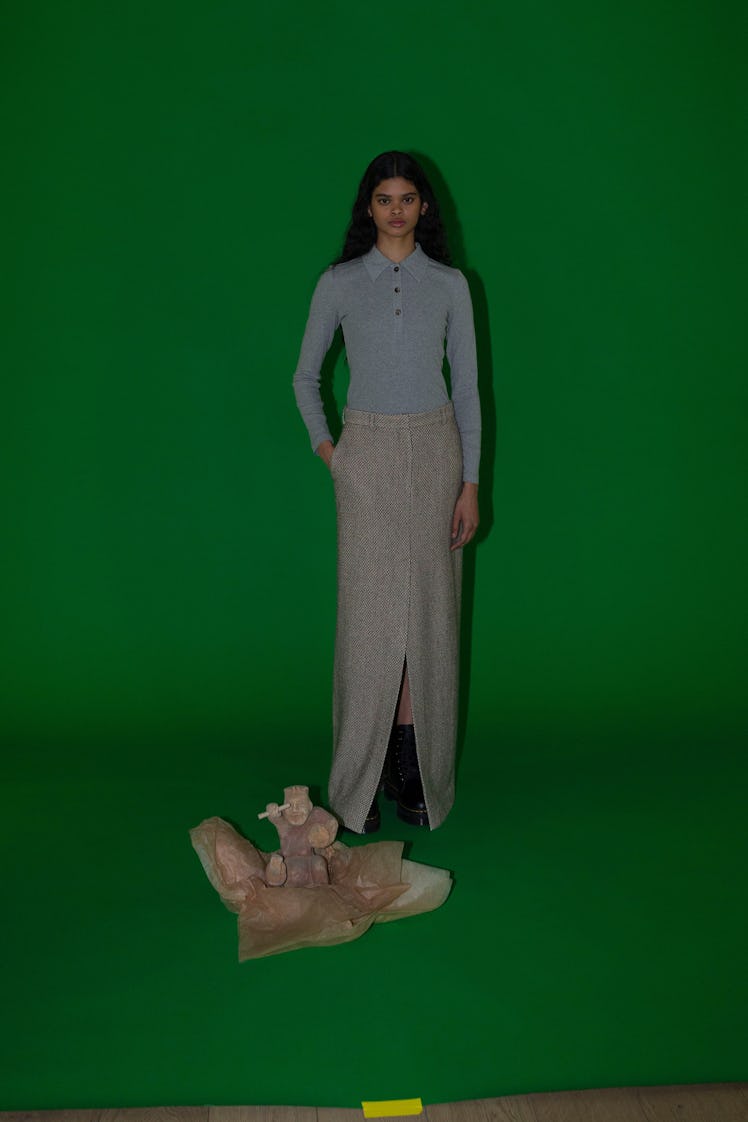 A model in a long-sleeved light blue shirt with a long grey skirt by Rosetta Getty