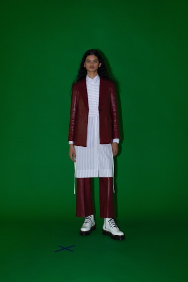A model in a maroon leather jacket with matching pants and a long white shirt by Rosetta Getty