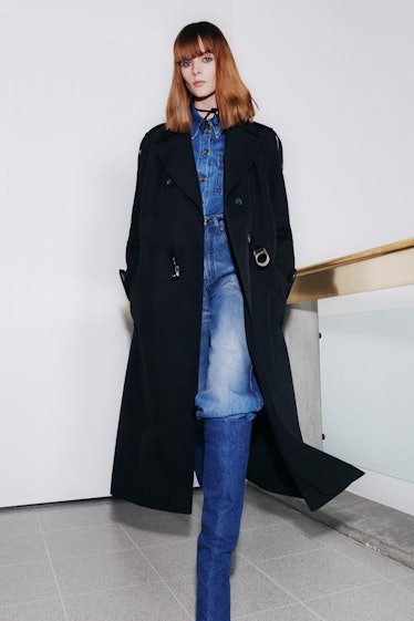 A model in a denim jumpsuit and a black overcoat by Victoria Beckham