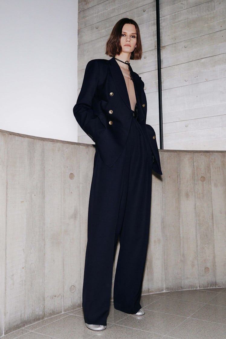 A model in a black blazer with a plunging neckline and high-waisted pants by Victoria Beckham
