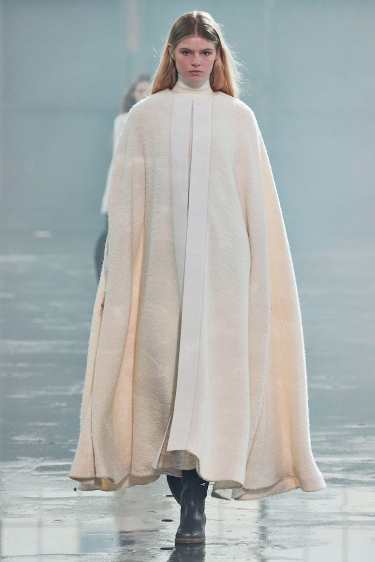 A model in a floor-length, long-sleeved poncho dress by Gabriela Hearst