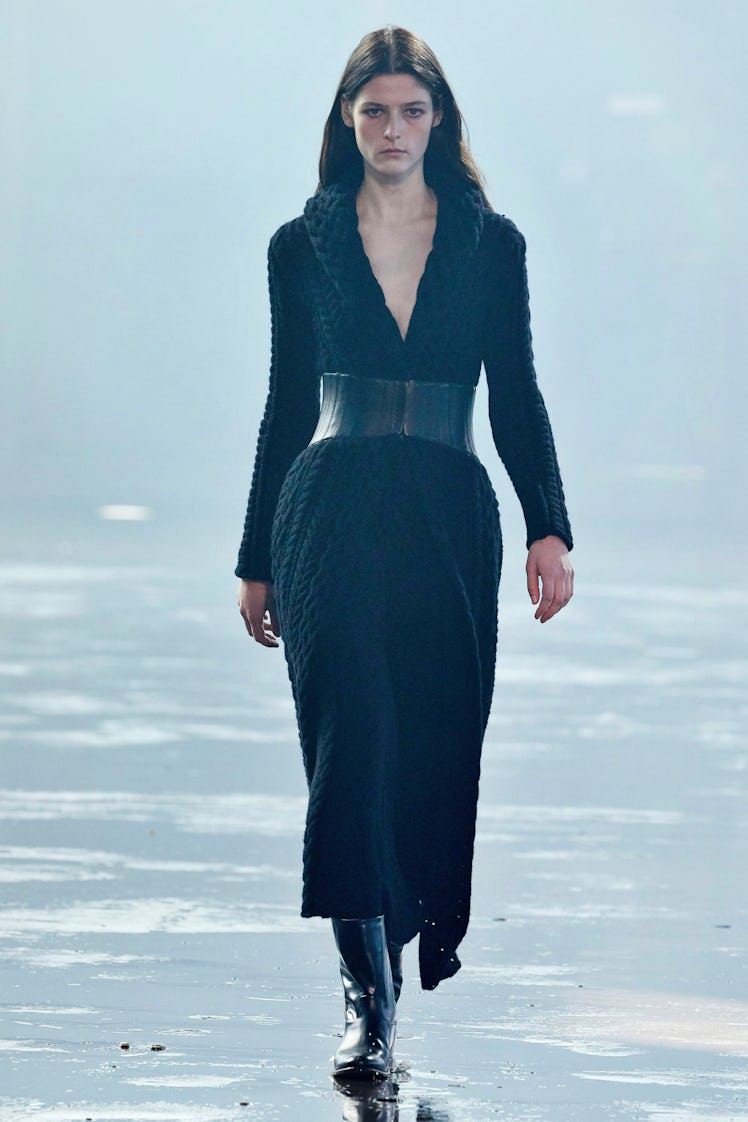 A model in a long knit dress, with a plunging neckline and a wide belt by Gabriela Hearst