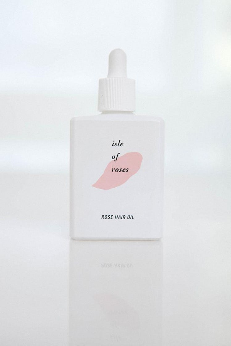 Isle of Roses Hair Oil in white packaging with simple font, and an illustrated smudge of pink
