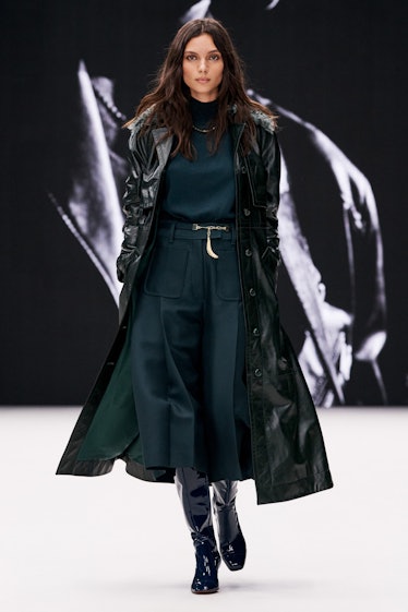 A model in a dark green jumpsuit and long leather coat by Zimmermann