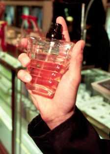 A male hand holding a bottle of perfume about to spray it. 