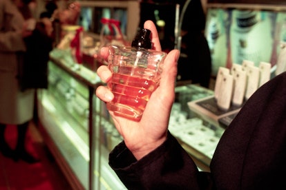 A male hand holding a bottle of perfume about to spray it. 