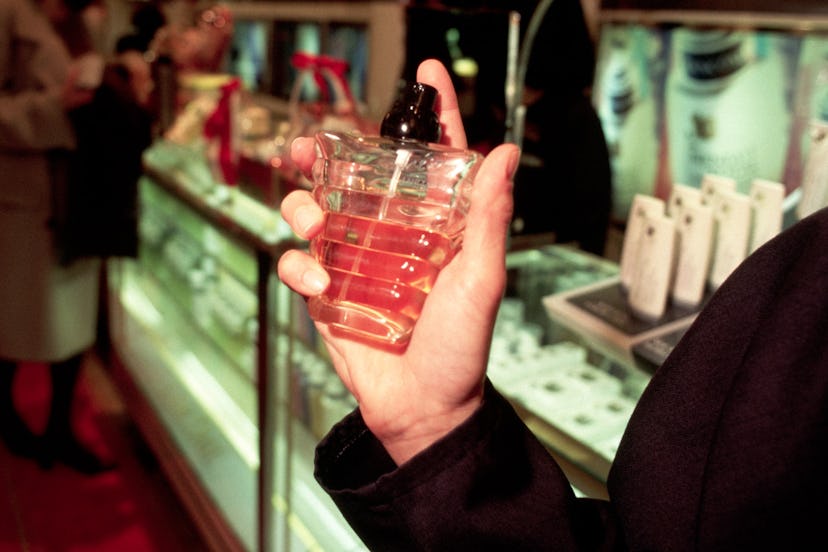 A male hand holding a bottle of perfume about to spray it.