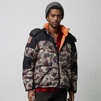 A man posing in a camo expedition down jacket from Denim & Supply