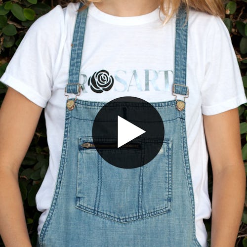 A model in a Metallic Rosarte T-Shirt and denim overalls, with a play button in the center of the ph...