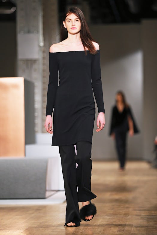 A model walking the runway in black outfit and matching Tibi's furry flats