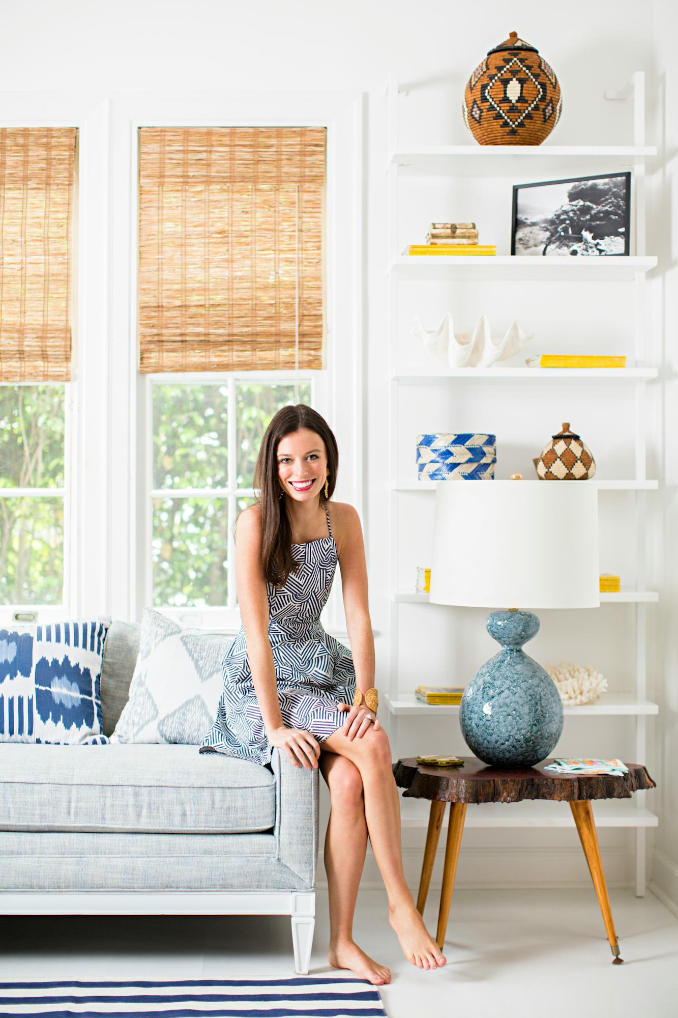 A woman sitting on the edge of a grey couch in her living room
