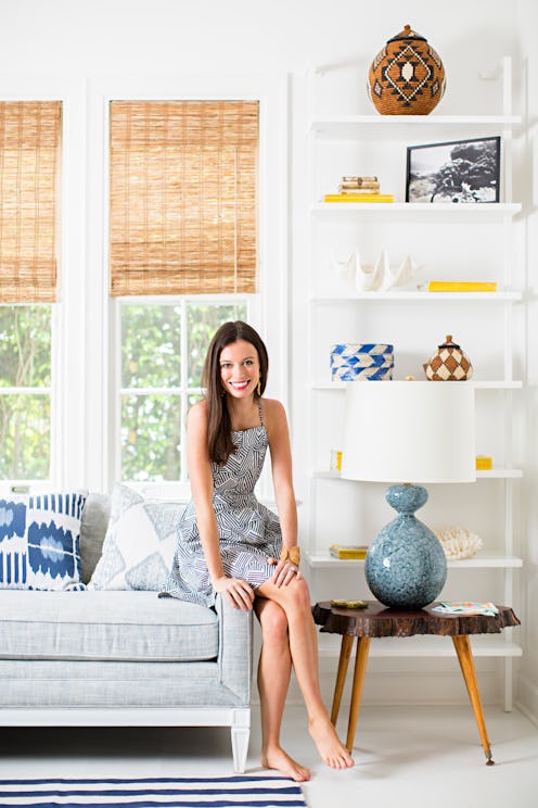 A woman sitting on the edge of a grey couch in her living room