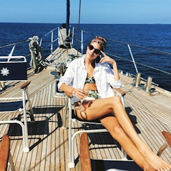 A model posing on a yacht in a white Endless Shirt J.Crew as a cover-up for her swimsuit 