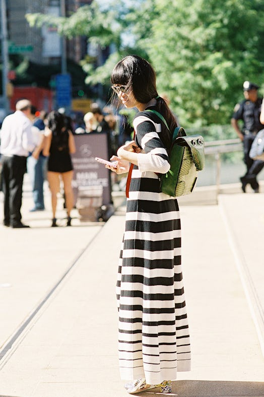 A woman wearing a black and white long dress and a backpack on a street