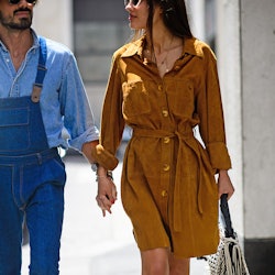A woman in a suede dress holding hands with a man in a denim shirt and denim overalls