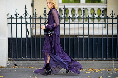 A woman walking down the street in a semi-sheer, dark blue dress for late summer
