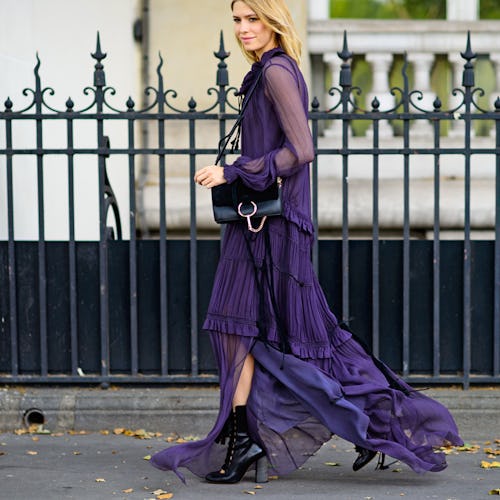 A woman walking down the street in a semi-sheer, dark blue dress for late summer