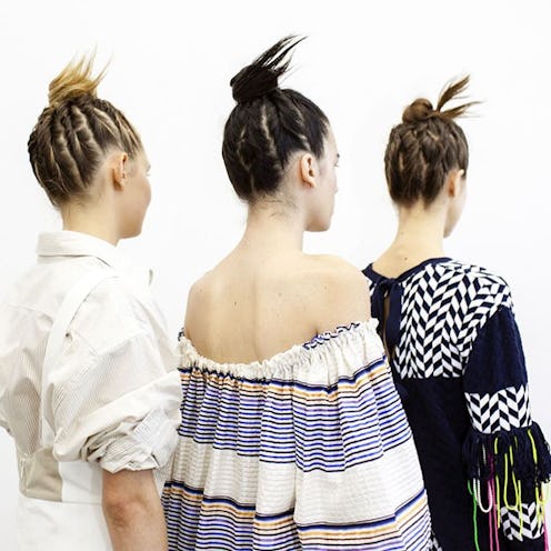 Three girls with braid buns posing with their backs turned