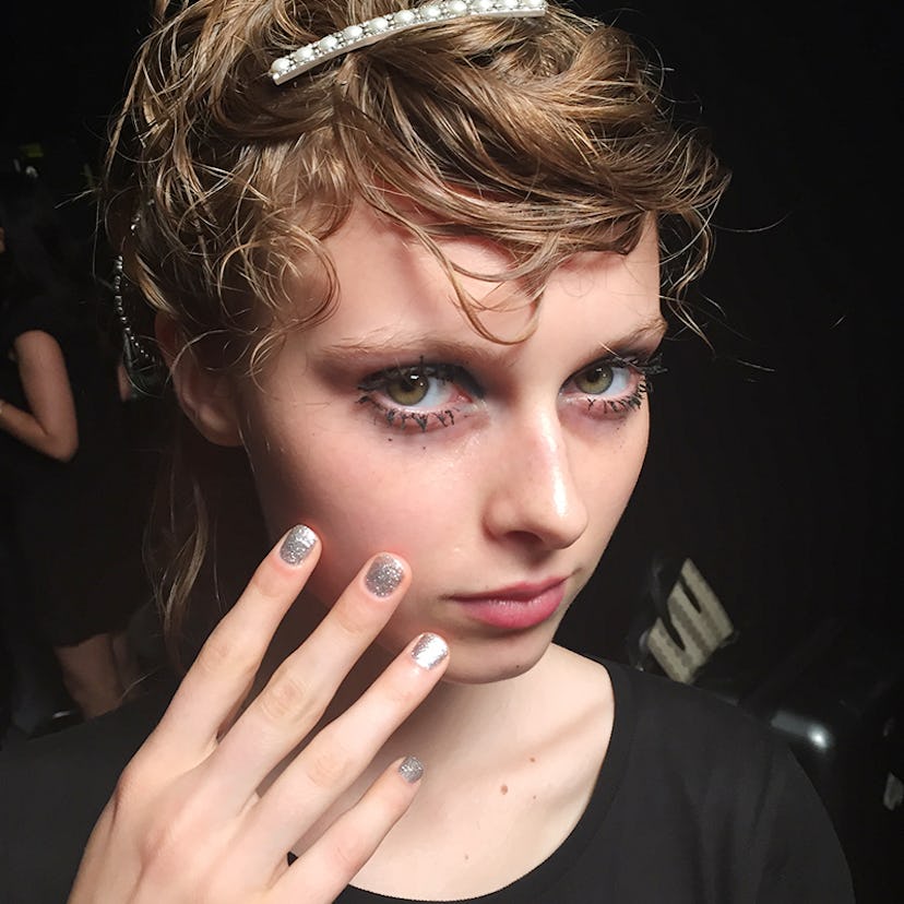 Model with dramatic makeup, showing her art deco manicure with silver glitter polish