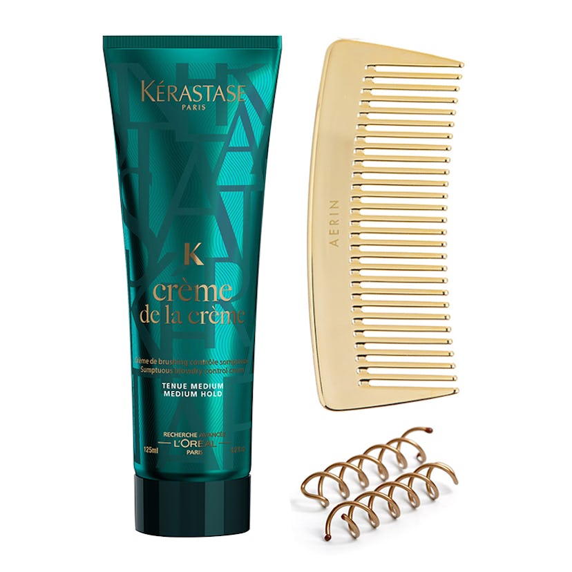 Creme de la creme blow dry cream tube, a travel gold-tone comb, and two spin pins on a white backgro...