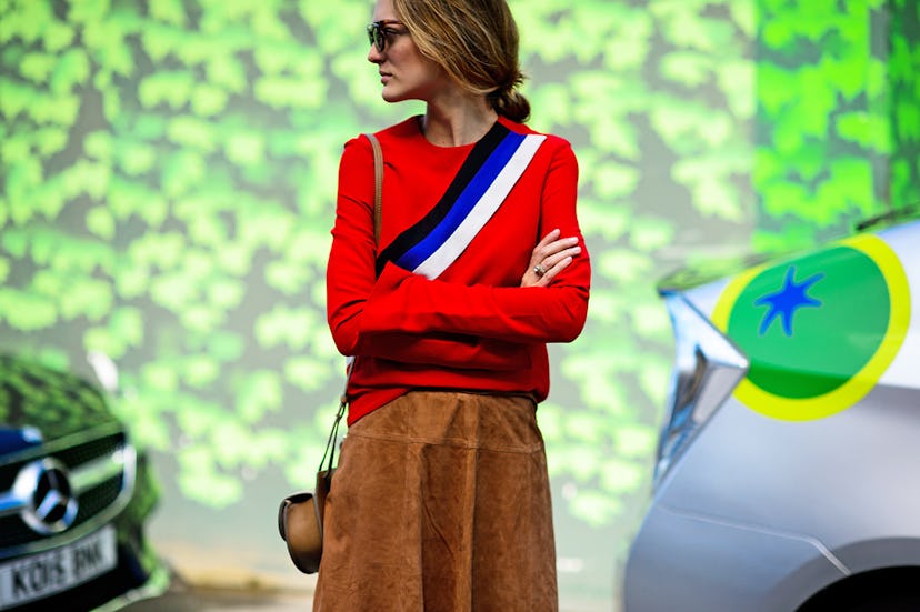A woman in a red-black-blue-white sweater and a caramel suede fall skirt