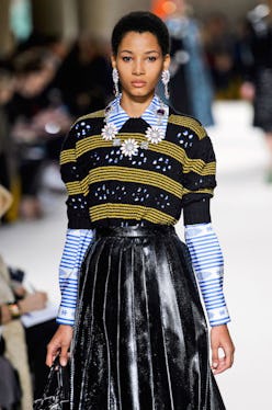 Lineisy Montero  walking the runway in a striped sweater, collared shirt and black leather skirt