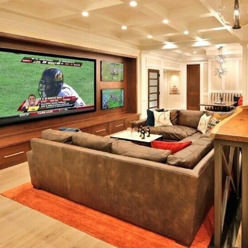 A living room with a big TV with a football game on the screen