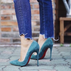 The closeup of a woman's legs in cropped jeans and turquoise suede pumps