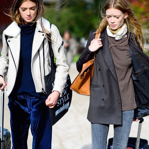 Two models walking with suitcases, in winter clothing, packed for a winter vacation