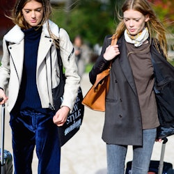 Two models walking with suitcases, in winter clothing, packed for a winter vacation