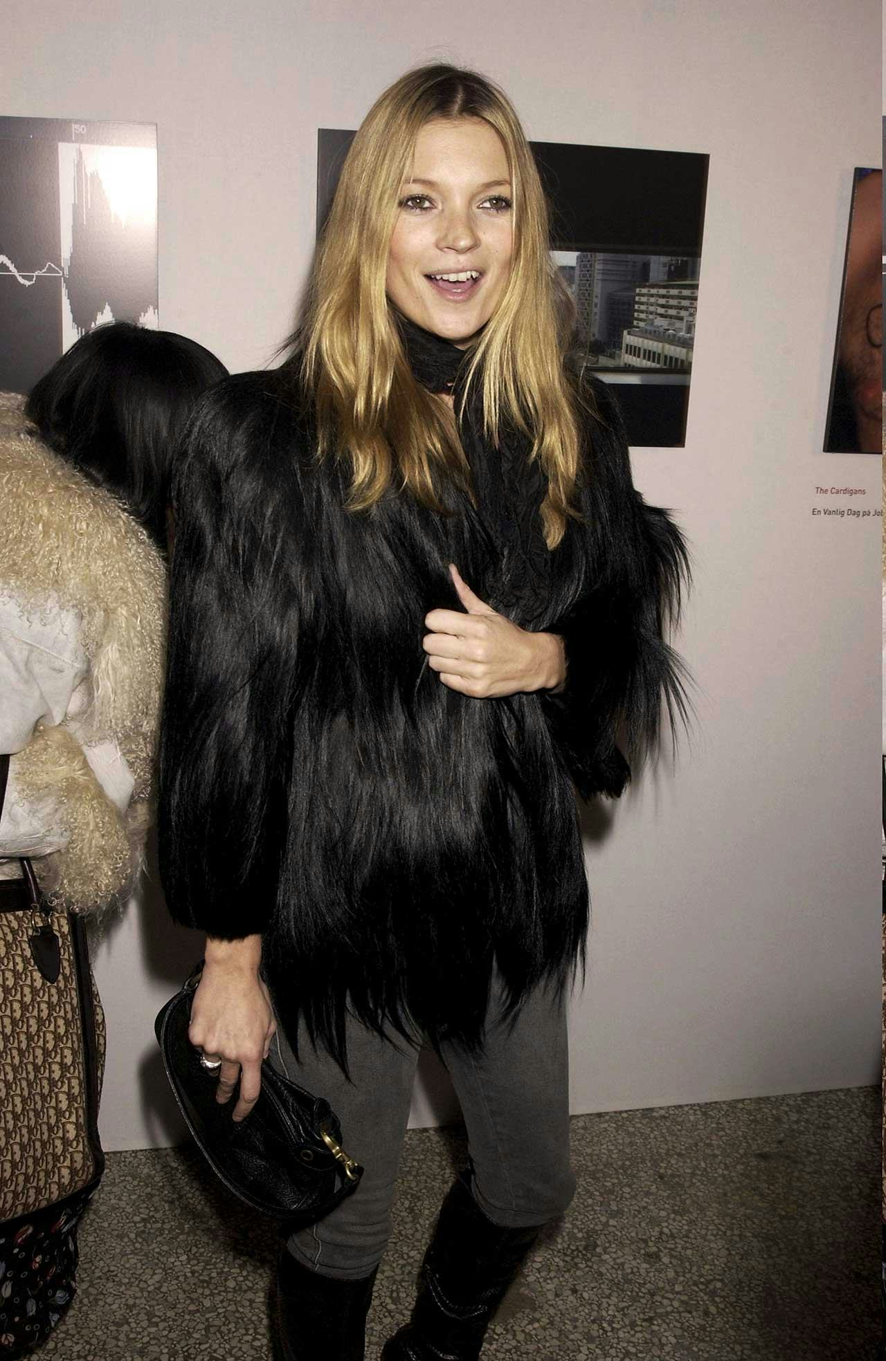 A woman in a faux fur coat, with a black handbag at her office party 
