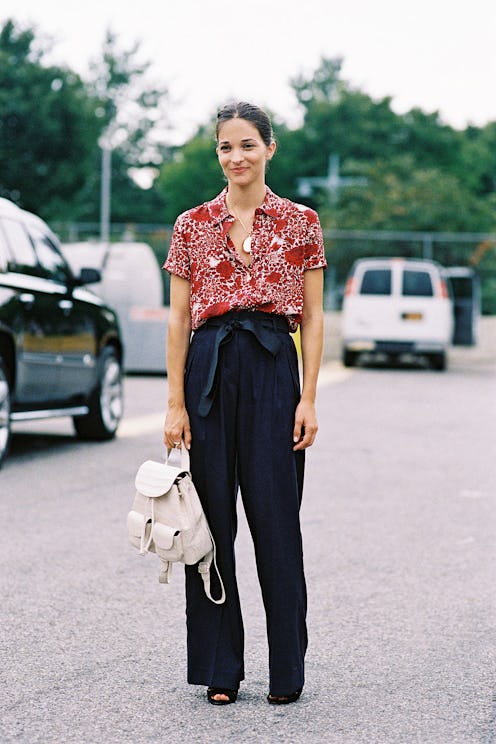 A woman in a red short-sleeved blouse and wide leg tie trousers