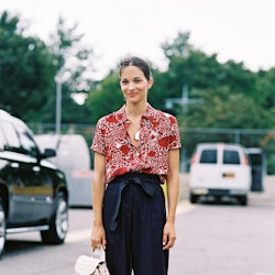 A woman in a red short-sleeved blouse and wide leg tie trousers