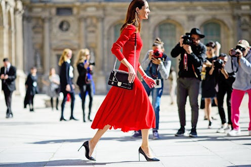 A woman walking on the street in a red Valentine's Day dress, a black bag and black heels