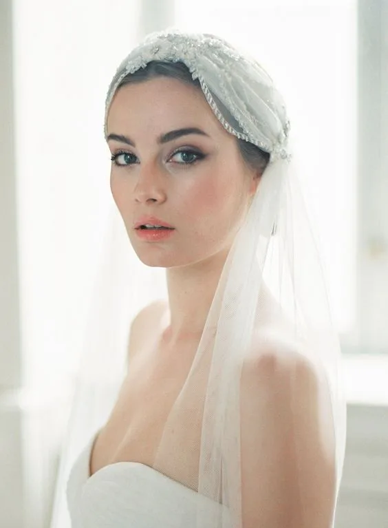 Bridal hairstyle featuring a sleek low bun paired beautifully with a sheer veil