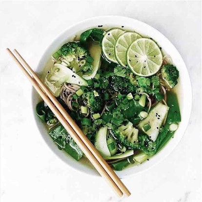 A bowl full of green vegetables and two chopsticks 