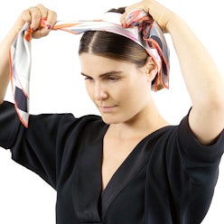 A woman styling a scarf as a headband 